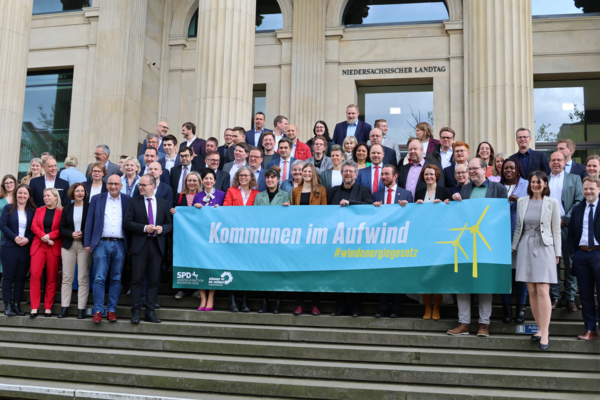 Foto der Abgeordneten der SPD und der Grünen vor dem Niedersächsischen Landtag. Sie halten ein Banner mit der Aufschrift "Kommunen im Aufwind #windenergiegesetz"